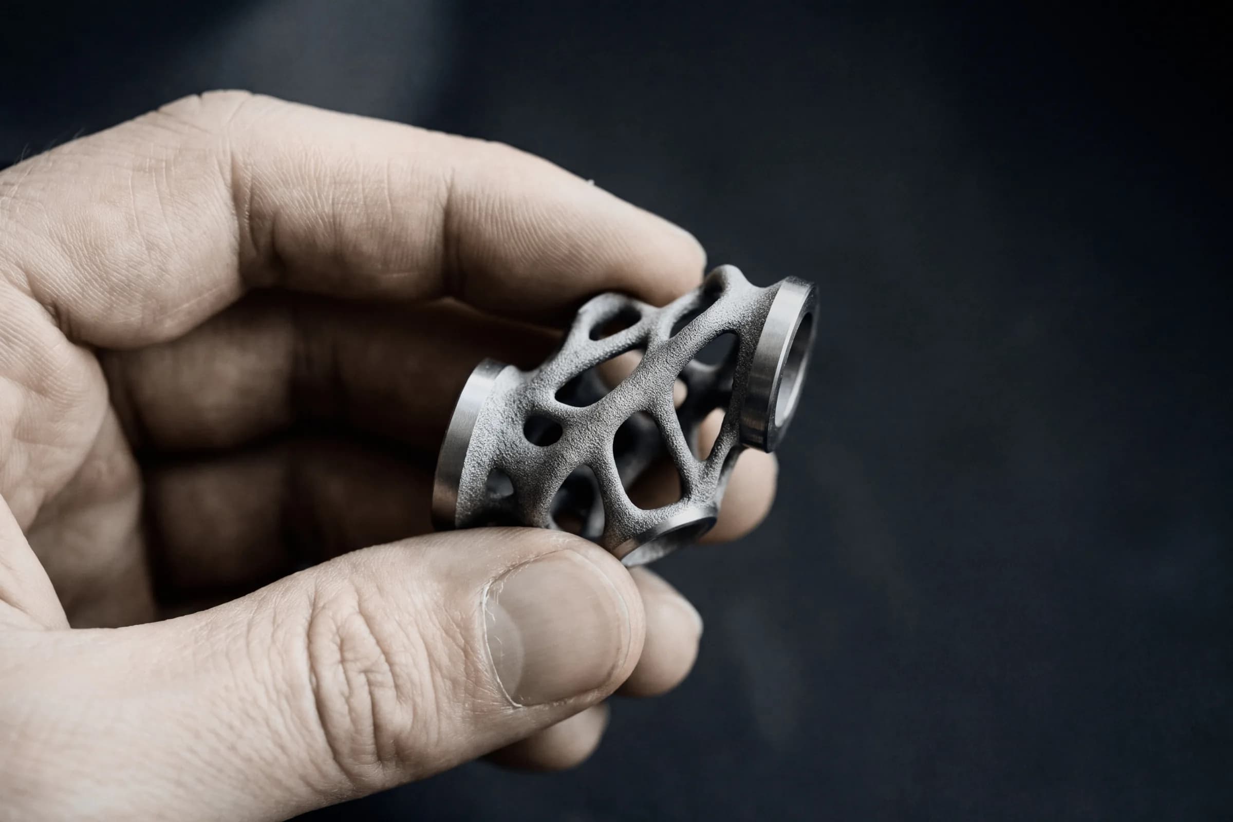 Fingers holding a printed metal lattice part