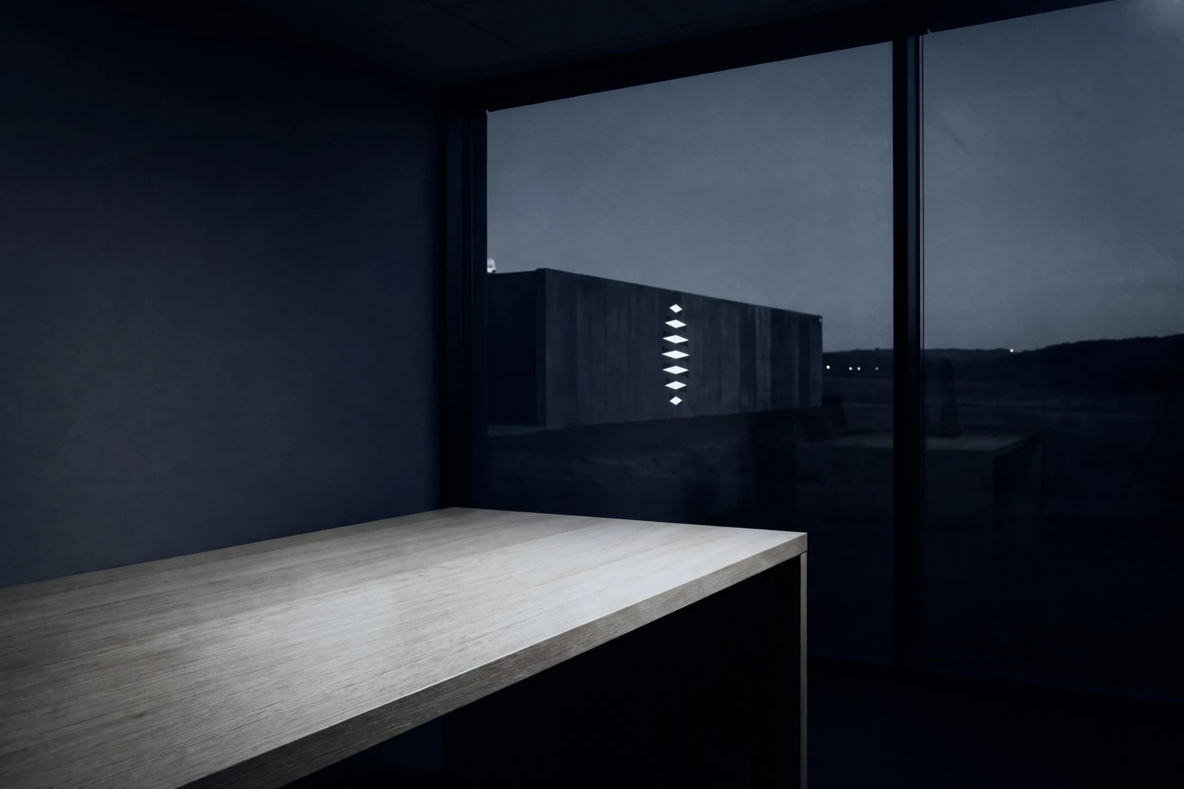 A dark room at dusk with a long table by the window